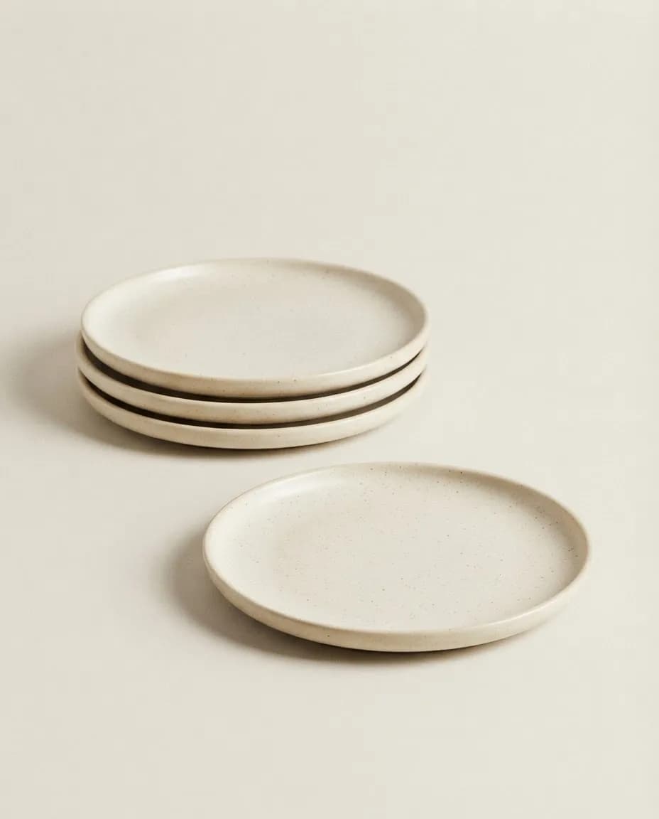 Stack of four ivory speckled stoneware dinner plates