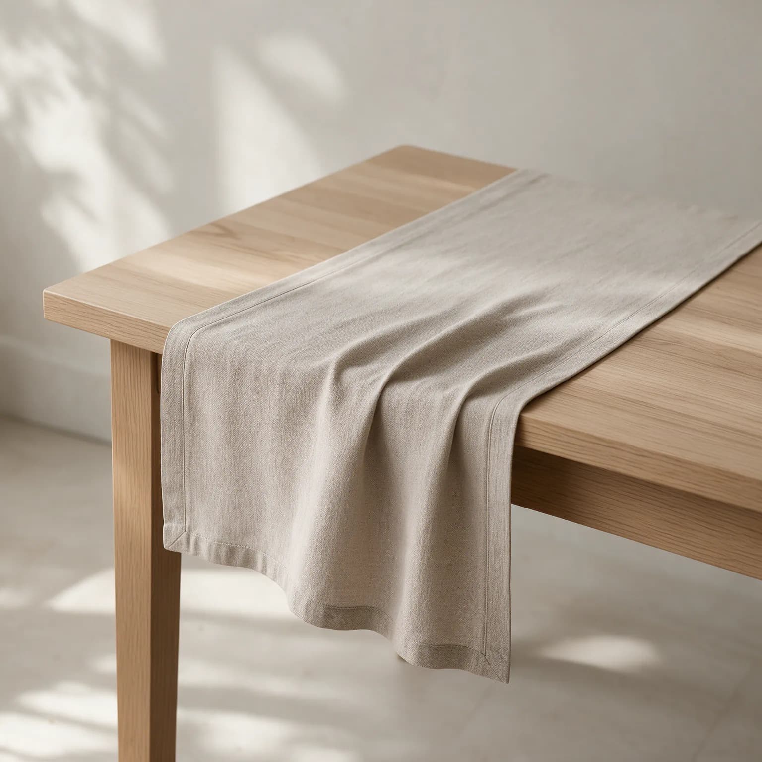 Oatmeal linen table runner draped across a wooden dining table